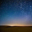 Fotomontaje tomado el 13 de agosto de 2021 que muestra el cielo nocturno durante la lluvia de meteoritos de las Perseidas sobre una zona de demostración ecológica de Engebei en el desierto de Kubuqi