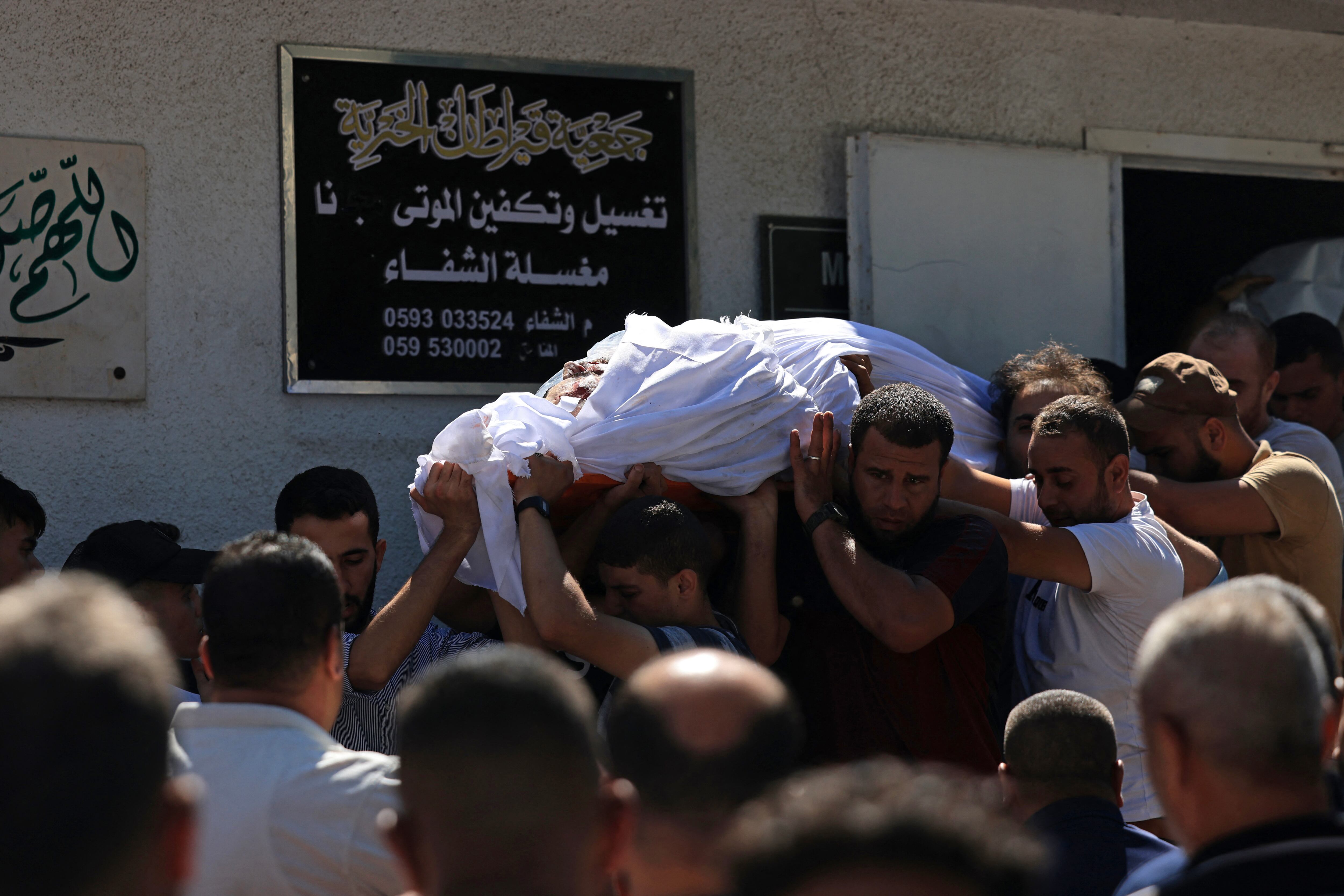 NOTA DEL EDITOR: Contenido gráfico / Dolientes llevan el cuerpo de un palestino fallecido en la última operación de infiltración en Israel, fuera del hospital al-Shifa en la Ciudad de Gaza el 7 de octubre de 2023. Según funcionarios israelíes, militantes palestinos han iniciado una "guerra" contra Israel, infiltrándose por aire, mar y tierra desde la bloqueada Franja de Gaza, lo que representa una escalada importante en el conflicto israelí-palestino. (Foto de MAHMUD HAMS / AFP).