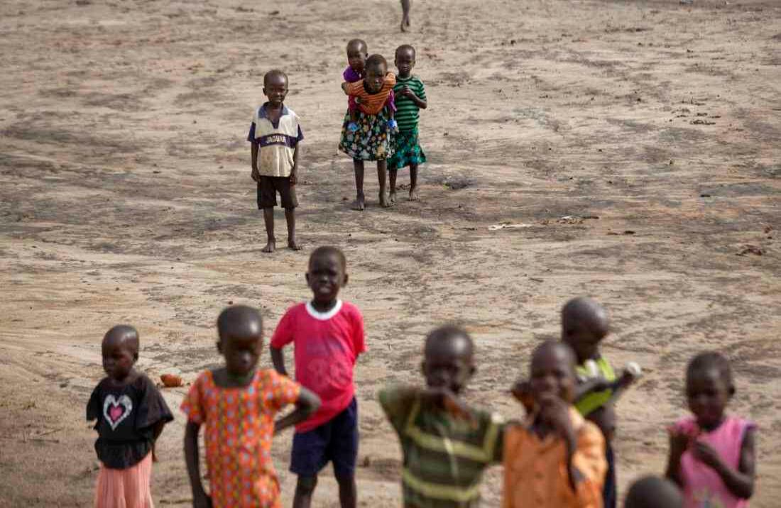 Una joven refugiada sudanesa lleva una bebé en su espalda mientras camina hacia la guardería de Ombechi, donde cuidará al bebé durante el día escolar (Foto de AP / Ben Curtis)  