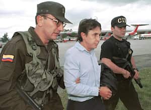 Prominent Colombian drug trafficker Fabio Ochoa Vasquez(C) is escorted by police as he arrives in Bogota 13 October 1999 shortly after he was captured along with another 29 narco-smugglers by Colombian authorities as part of a massive international sting operation code-named "Operation Millennium"involving the US, Mexico and Ecuador. AFP PHOTO/COLOMBIAN POLICE (Photo by JAVIER CASELLA / COLOMBIAN POLICE / AFP)