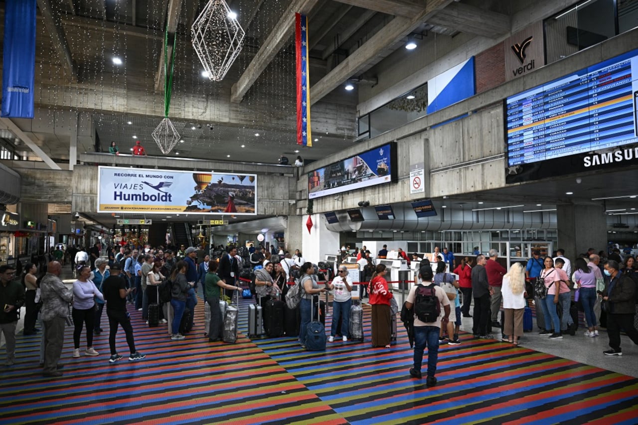 Passengers queue at counters at Simon Bolivar International Airport in Maiquetia, La Guaira State, Venezuela, on November 27, 2025. Venezuela's decision to ban foreign airlines that stopped flying to the Caribbean country over concerns about US military activity was branded "disproportionate" on Thursday as thousands of passengers scrambled to save their travel plans. (Photo by Federico PARRA / AFP)