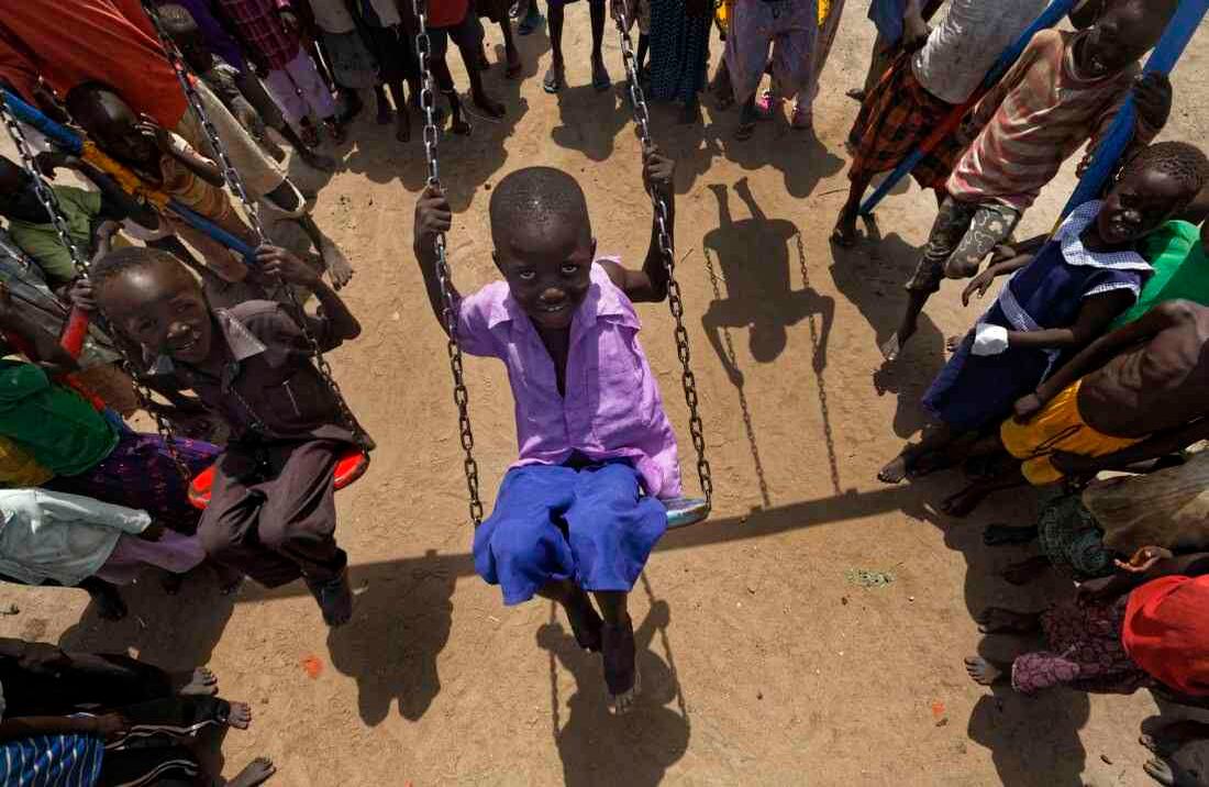 Los niños sudaneses refugiados juegan en columpios durante el almuerzo en el patio de la guardería Ombechi (Foto de AP / Ben Curtis)