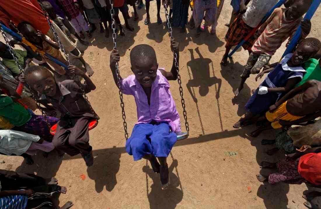 Los niños sudaneses refugiados juegan en columpios durante el almuerzo en el patio de la guardería Ombechi (Foto de AP / Ben Curtis)