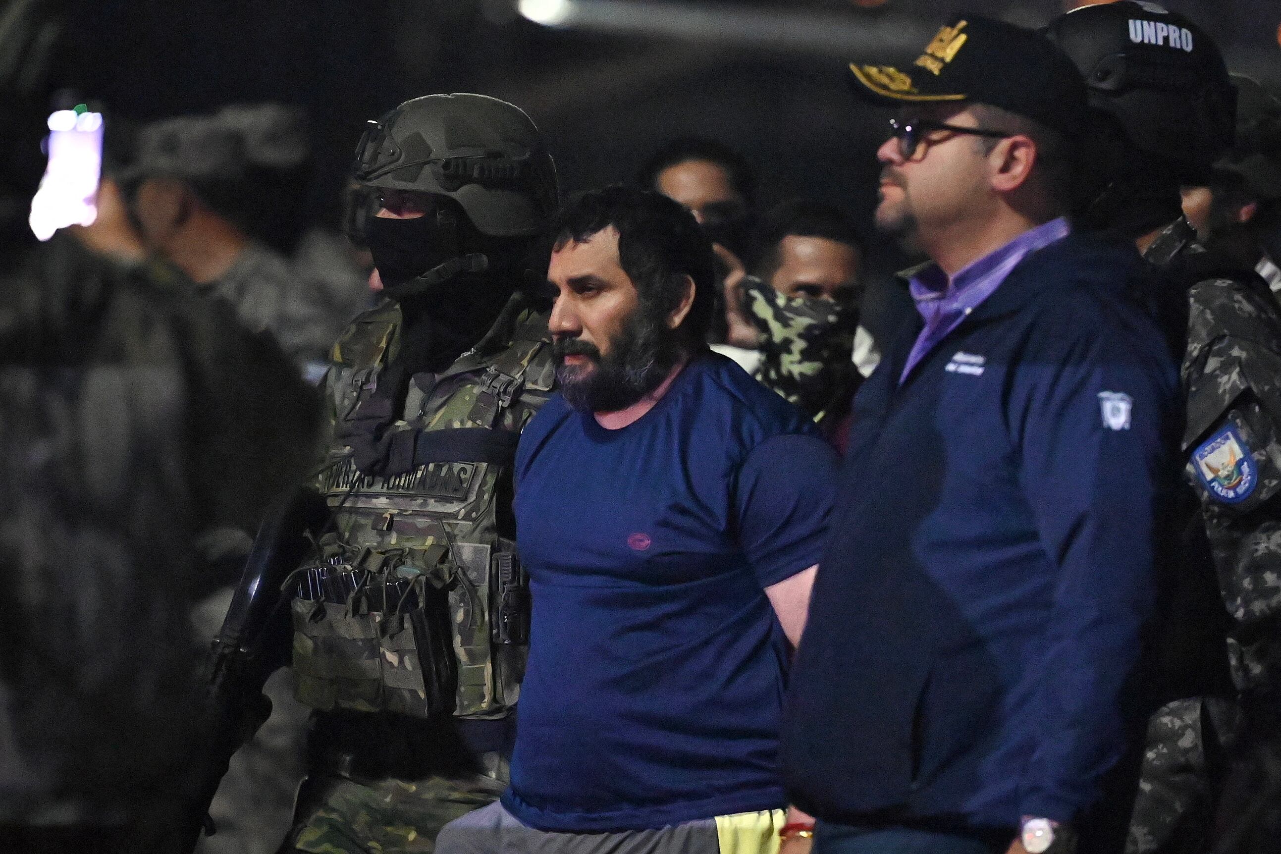 El narcotraficante Adolfo Macías, alias Fito, es custodiado por el ministro del Interior de Ecuador, John Reimberg (der.), y personal militar a su llegada a la base aérea de Guayaquil, Ecuador, el 25 de junio de 2025,