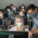 Profesor que llevaba una mascarilla y ayudando a la alumna a una clase de TI - educación durante la pandemia COVID-19