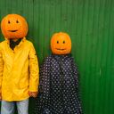 Photo of a couple with pumpkins on the heads, ready for the Halloween.