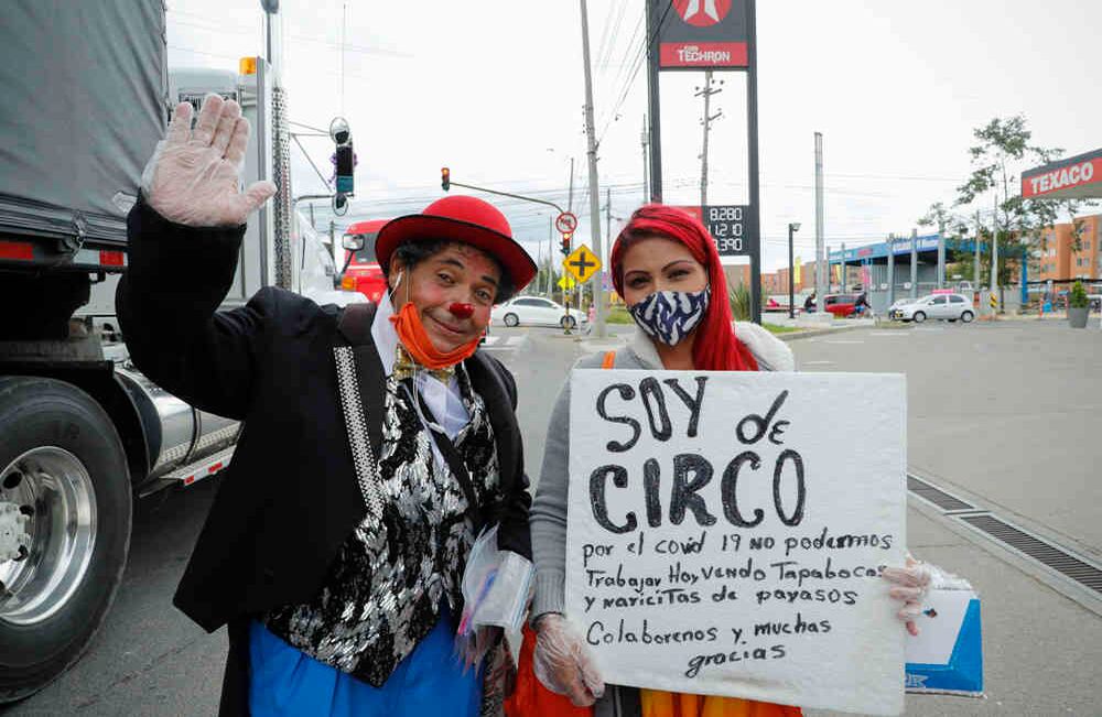 Juan Carlos Morales mide solo 1,55 centímetros, pero se considera un gigante para sacarle sonrisas a la gente. Como el circo cerró, decidió de la mano de su hija Beatriz alternar lo que sabe hacer con vender tapabocas y narices de payaso. Tiene un proyecto a corto plazo: “Estamos trabajando en un show de circo a domicilio. Uno que haga reír a los niños a través de las ventanas de las casas”, dice.  Foto: Guillermo Torres SEMANA