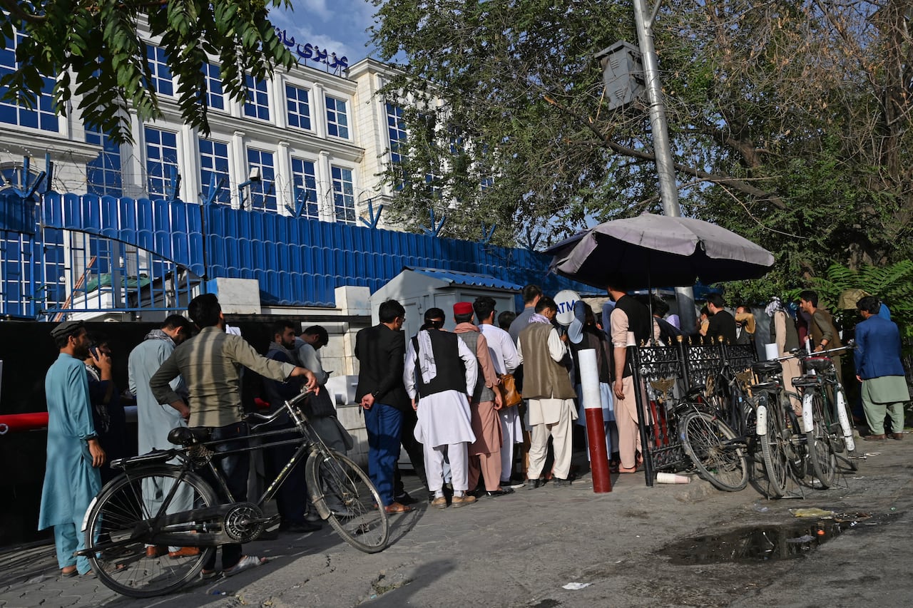 Los afganos hacen cola mientras esperan su turno para cobrar dinero de un cajero automático frente a un banco a lo largo de una carretera en Kabul el 21 de agosto de 2021, días después de la impresionante toma de Afganistán por los talibanes. (Foto por - / AFP)