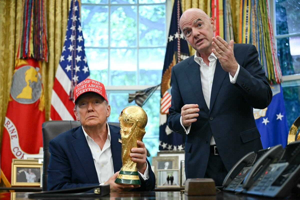 El presidente de Estados Unidos, Donald Trump, acompañado por el presidente de la FIFA, Gianni Infantino (derecha), sostiene el trofeo de la Copa del Mundo mientras hace un anuncio en la Oficina Oval.