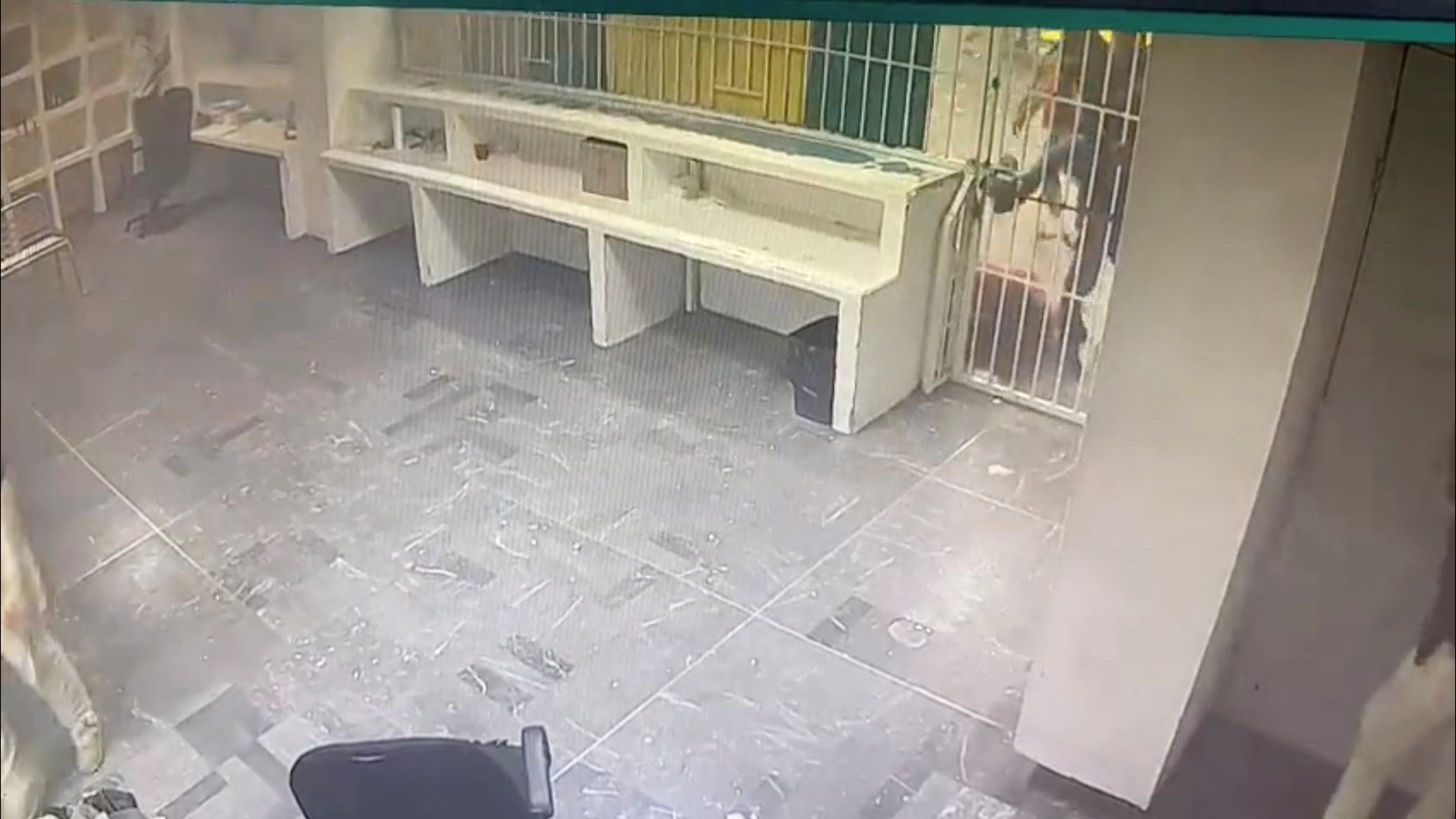 Un migrante detenido patea la puerta de una celda cerrada mientras el fuego se propaga desde el interior mientras los oficiales uniformados observan un centro de detención de migrantes en Ciudad Juárez