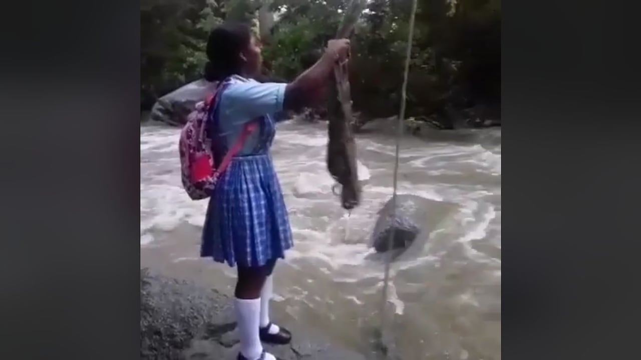 Una niña intenta cruzar el río Gaira mediante una polea improvisada.