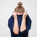 Mujer europea escondiendo la cara debajo de la ropa. Ella está tirando suéter en su cabeza. Emoción deprimida. Deseo estar solo.