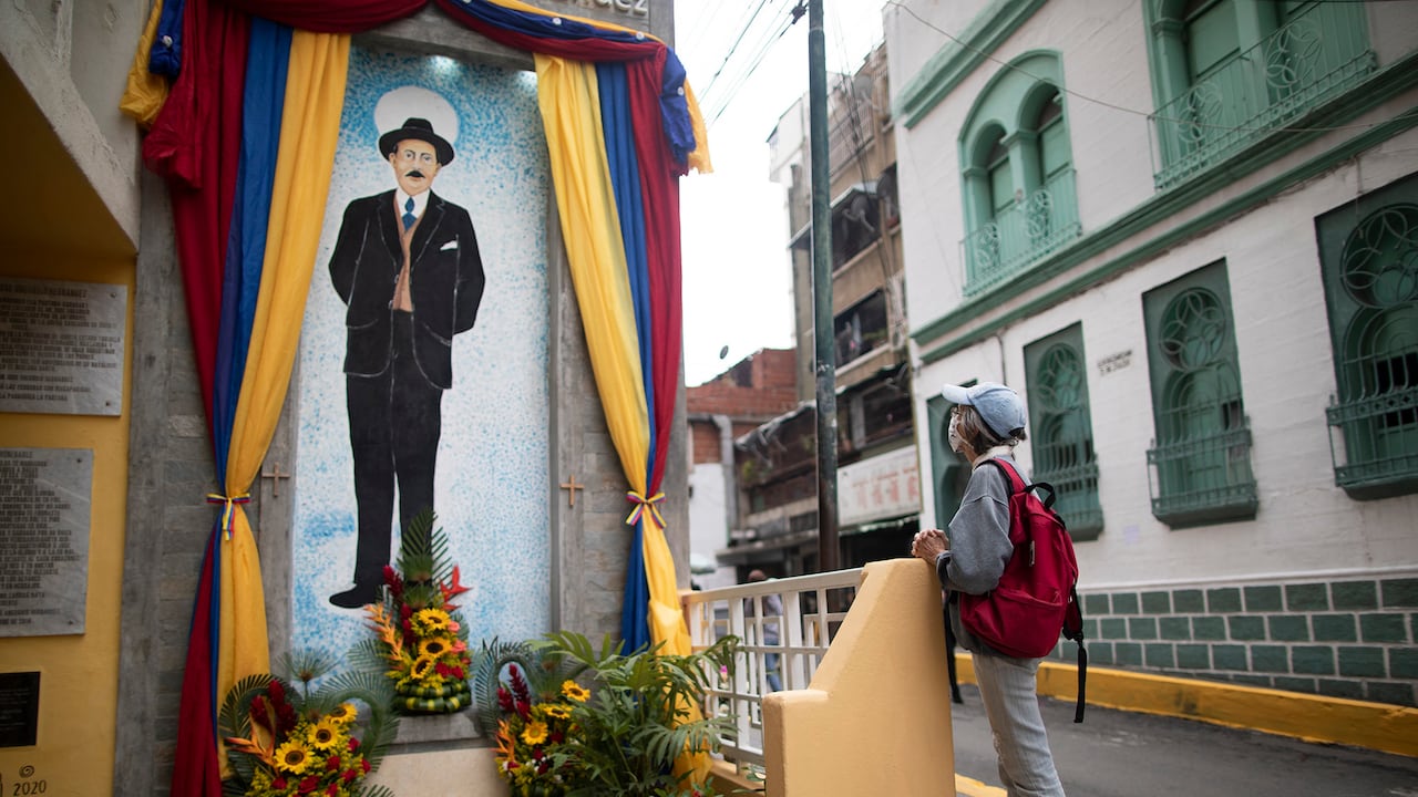 Una mujer reza cerca de un cuadro con la imagen de José Gregorio Hernández en la calle donde murió en un accidente automovilístico en 1919, en el barrio La Pastora de Caracas, Venezuela, el 28 de abril de 2021. Conocido como el "médico de los pobres Hernández será beatificado el 30 de abril por la Iglesia Católica, un paso hacia su santidad. (Foto AP / Ariana Cubillos)