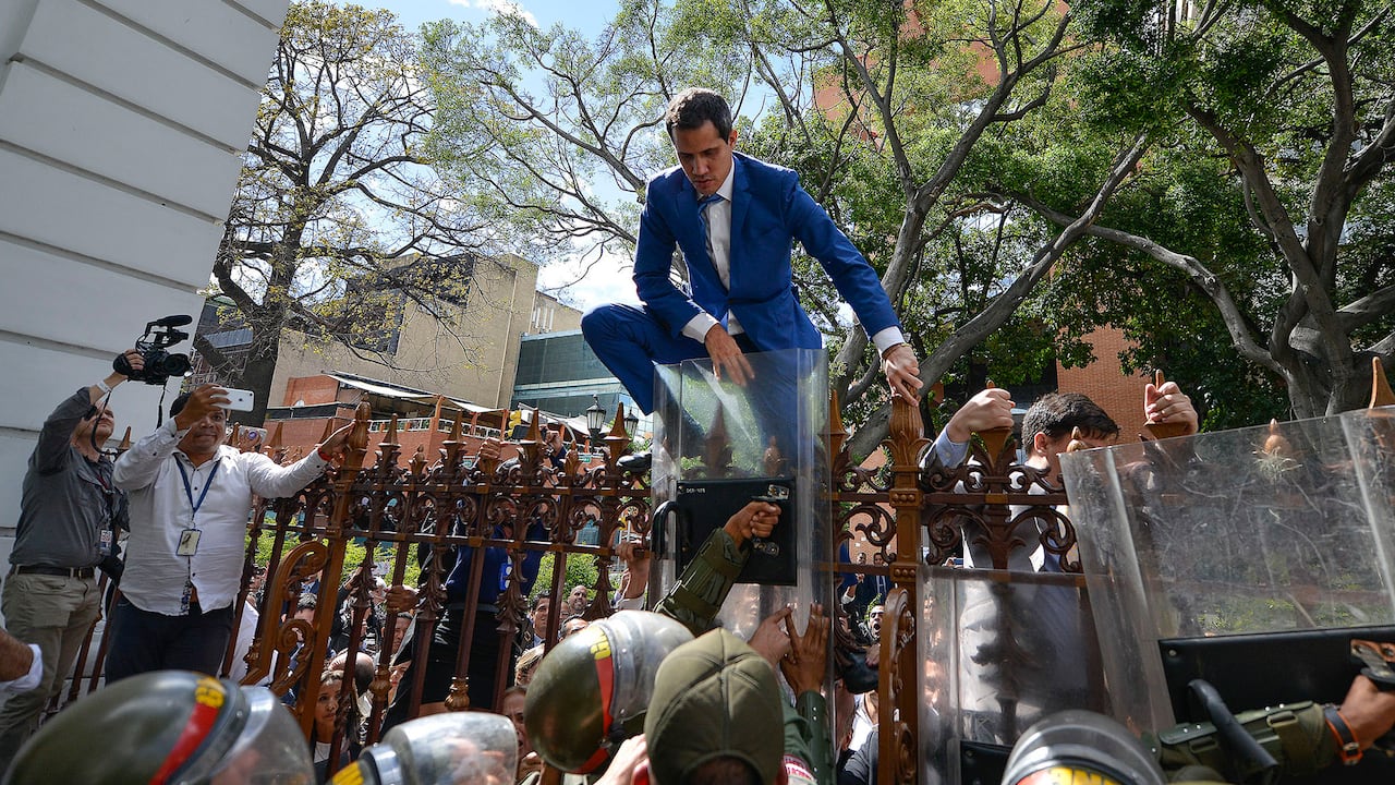 El presidente de la Asamblea Nacional, Juan Guaidó, líder de la oposición de Venezuela, trepa la cerca en un intento fallido de ingresar al recinto legislativo para una sesión en que elegirían al nuevo líder del organismo en Caracas, Venezuela, el domingo 5 de enero de 2020. Foto: AP / Matías Delacroix.
