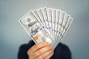 Manos sosteniendo dólares en efectivo. 1000 dólares en billetes de 100 en el primer plano de la mano de un hombre sobre un fondo oscuro.concepto.