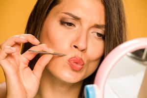 woman plucking her mustache with tweezers