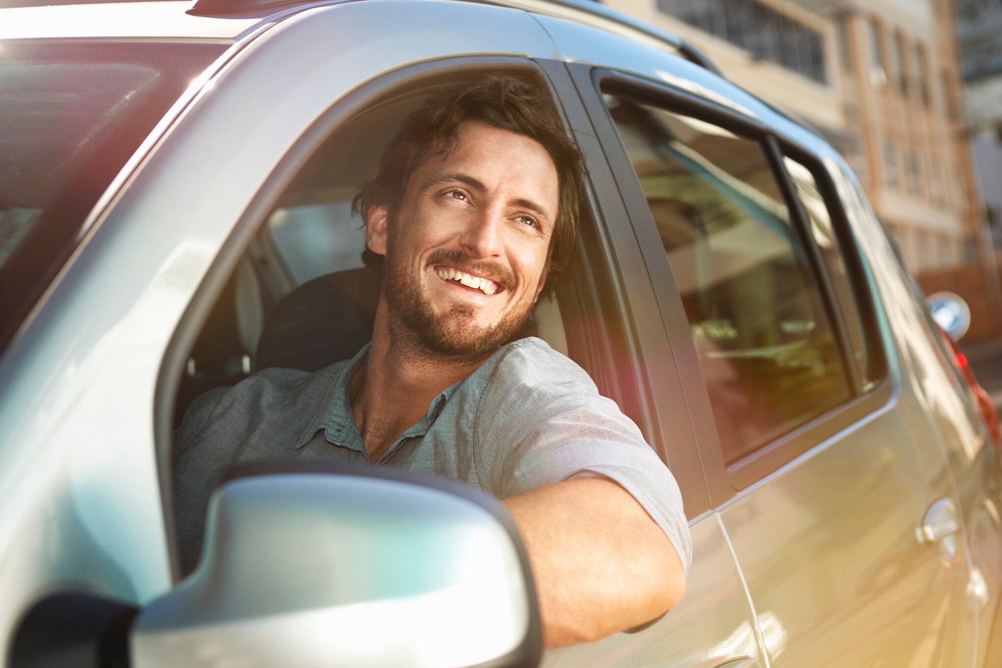 Hombre joven que mira fuera de la ventana del coche