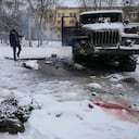 The body of a serviceman is coated in snow as a man takes photos of a destroyed Russian military multiple rocket launcher vehicle on the outskirts of Kharkiv, Ukraine, Friday, Feb. 25, 2022. Russian troops bore down on Ukraine's capital Friday, with gunfire and explosions resonating ever closer to the government quarter, in an invasion of a democratic country that has fueled fears of wider war in Europe and triggered worldwide efforts to make Russia stop. (AP Photo/Vadim Ghirda)