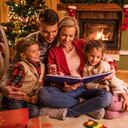 Young happy family reading fairy tales while relaxing at home during Christmas holidays.