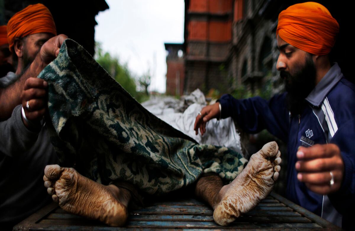 Hombres de la India cubren el cuerpo del comerciante Gurmeet Singh, cuyo cuerpo sin vida fue hallado en medio de las inundaciones, que han cobrado más de 200 vidas. (AP)