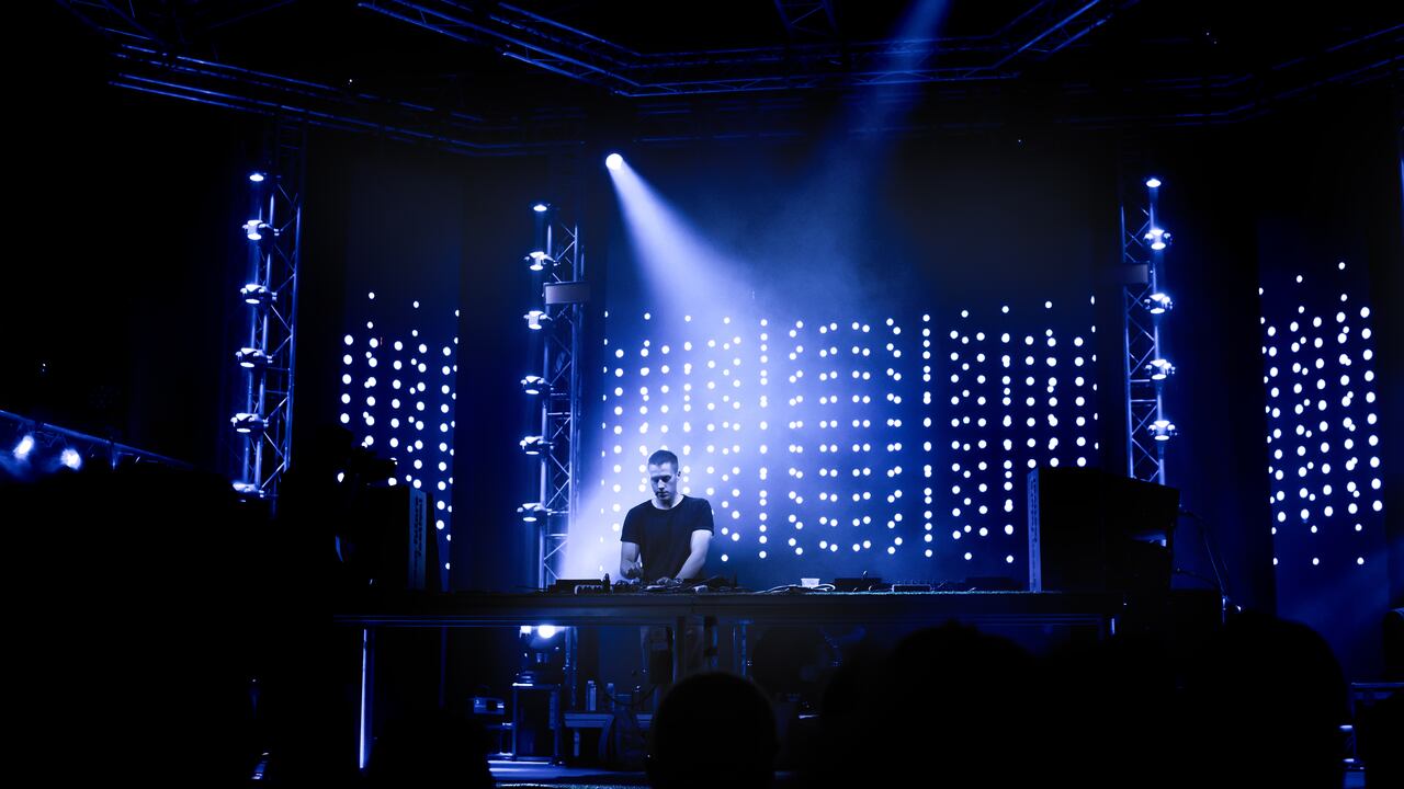 Dj playing techno music on the stage during night concert.