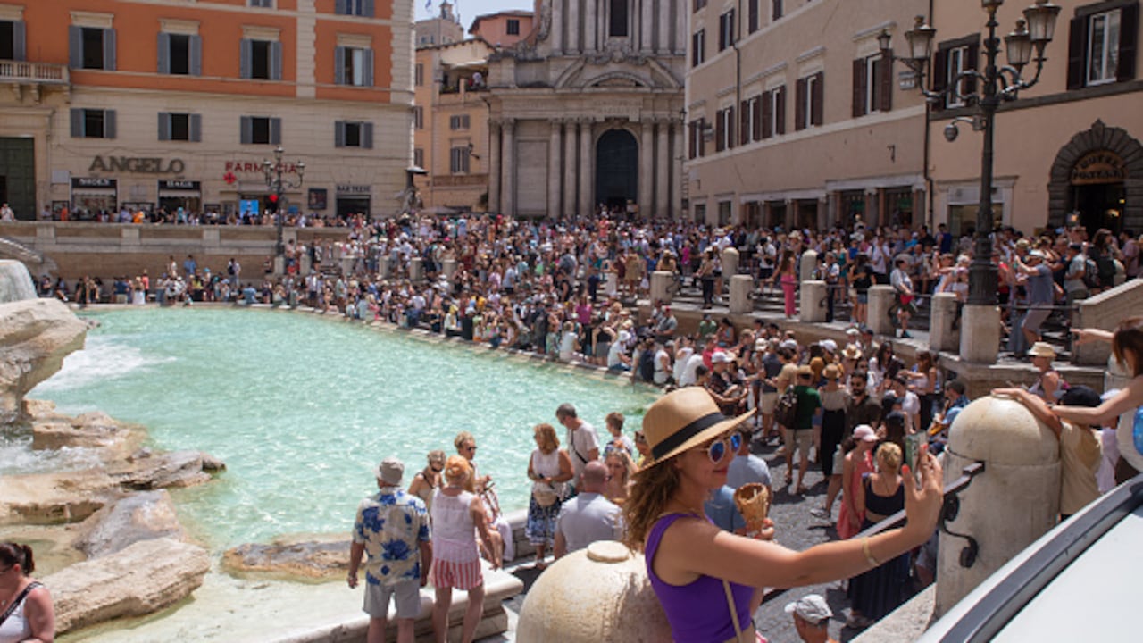 Turistas se enfrentan al fuerte sol en Roma, Italia.