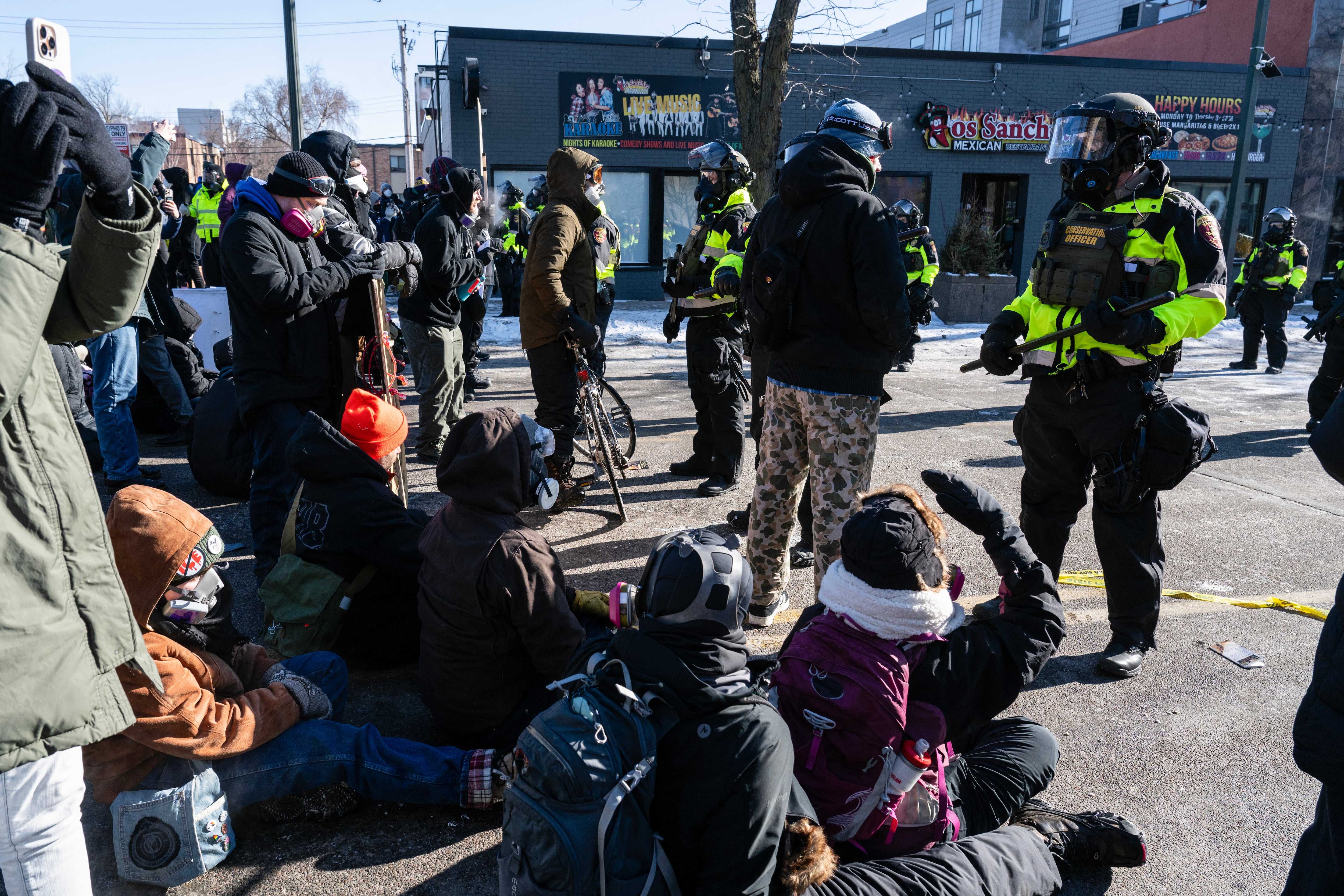 Minnesota Department of Natural Resources Conservation Officers stand guard as demonstrators gather near the site of where state and local authorities say a man was shot and killed by federal agents earlier in the morning in Minneapolis, Minnesota, on January 24, 2026. Federal immigration agents shot dead a man in Minneapolis on Saturday, officials said -- the second fatal shooting of a civilian in the city, sparking fresh protests and outrage from state officials. The death came less than three weeks after US citizen Renee Good was shot and killed by an Immigration and Customs Enforcement officer involved in sweeps to round up undocumented migrants. (Photo by ROBERTO SCHMIDT / AFP)