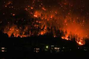 El incendio forestal de McDougall Creek arde en la ladera de la montaña sobre las casas en West Kelowna, B.C., el viernes 18 de agosto de 2023. Miles han huido, conduciendo cientos de kilómetros (millas) para ponerse a salvo o esperando en largas filas para vuelos de emergencia, como lo peor la temporada de incendios registrada en Canadá no mostró signos de alivio. (Darryl Dyck/The Canadian Press vía AP)