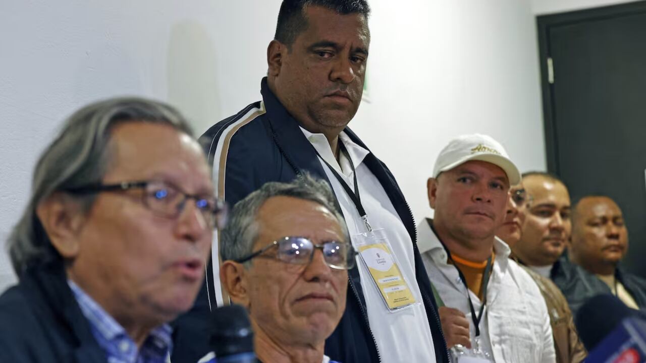 El jefe de los Comandos de Frontera, Giovanny Andrés Rojas (de pie), observa al jefe negociador del Gobierno, Armando Novoa (a la izquierda), y al de la Coordinadora Nacional Ejército Bolivariano, 'Walter Mendoza', durante una rueda de prensa en Bogotá, el martes 26 de noviembre de 2024.