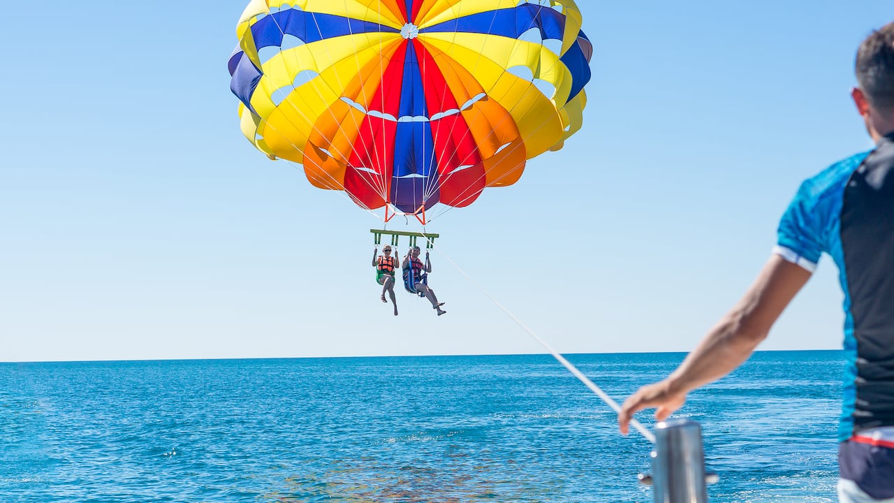 Pareja feliz haciendo parasailing en playa dominicana en verano