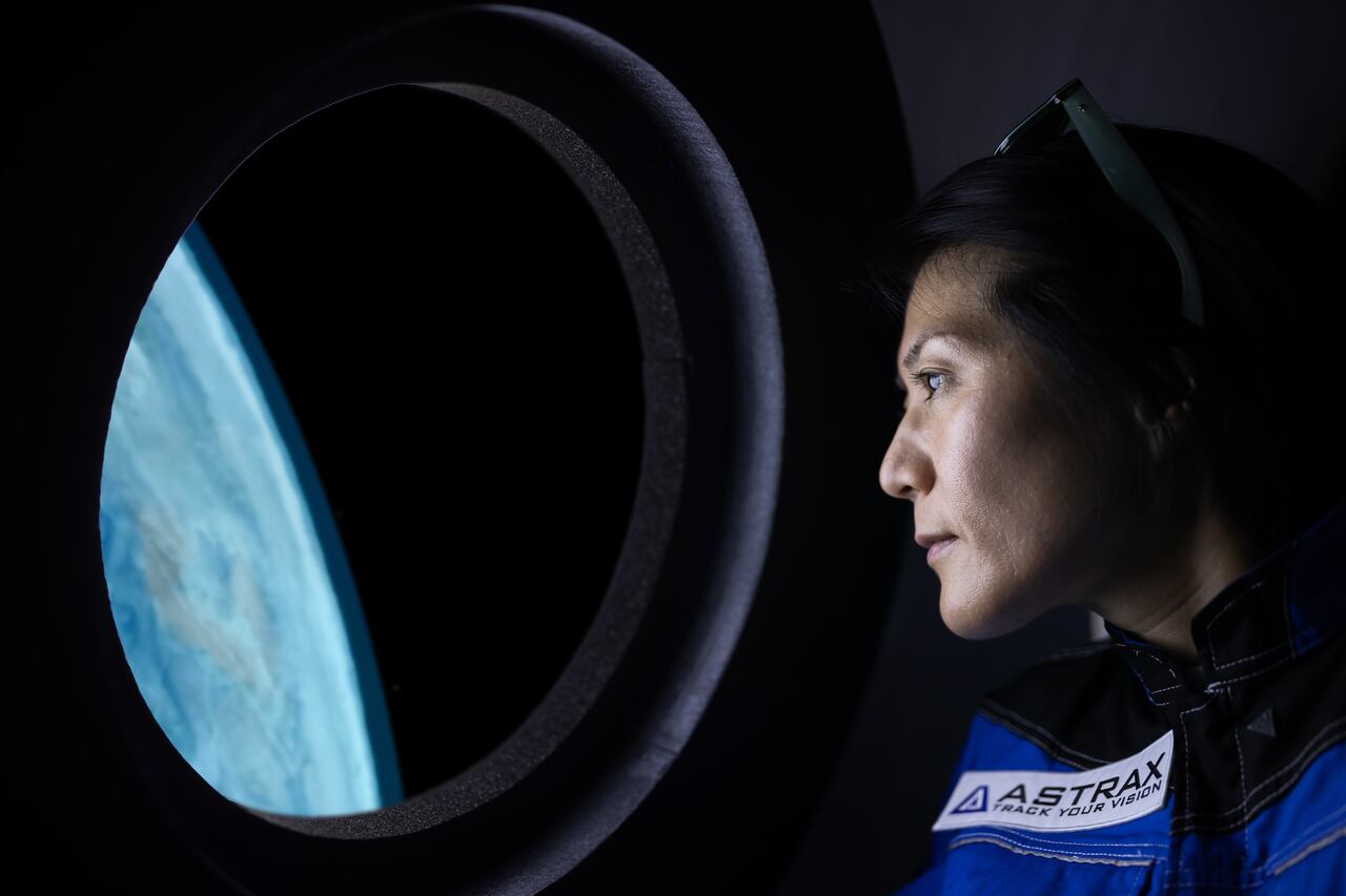 A commercial space traveler looking at the earth throughout the window at inside of the spaceship.