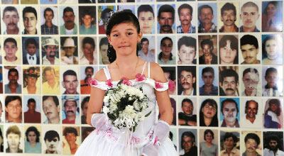 Granada.
Cientos de fotos
de víctimas del
conflicto adornan
los muros del
Salón del Nunca
Más en Granada,
Antioquia. Aquí,
una niña posa
junto al muro
donde se encuentra
la imagen de
su padre para su
foto de primera
comunión.