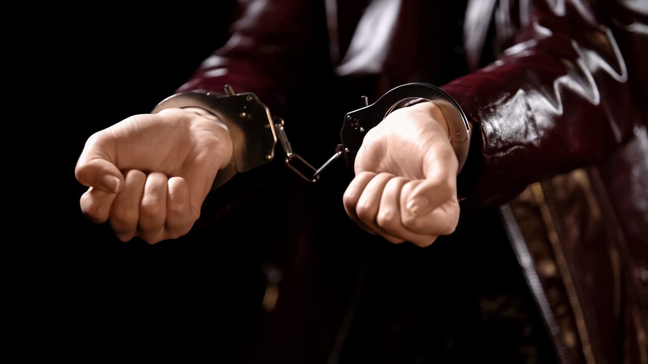 Police officer arrests young woman for prostitution, hands handcuffed close up