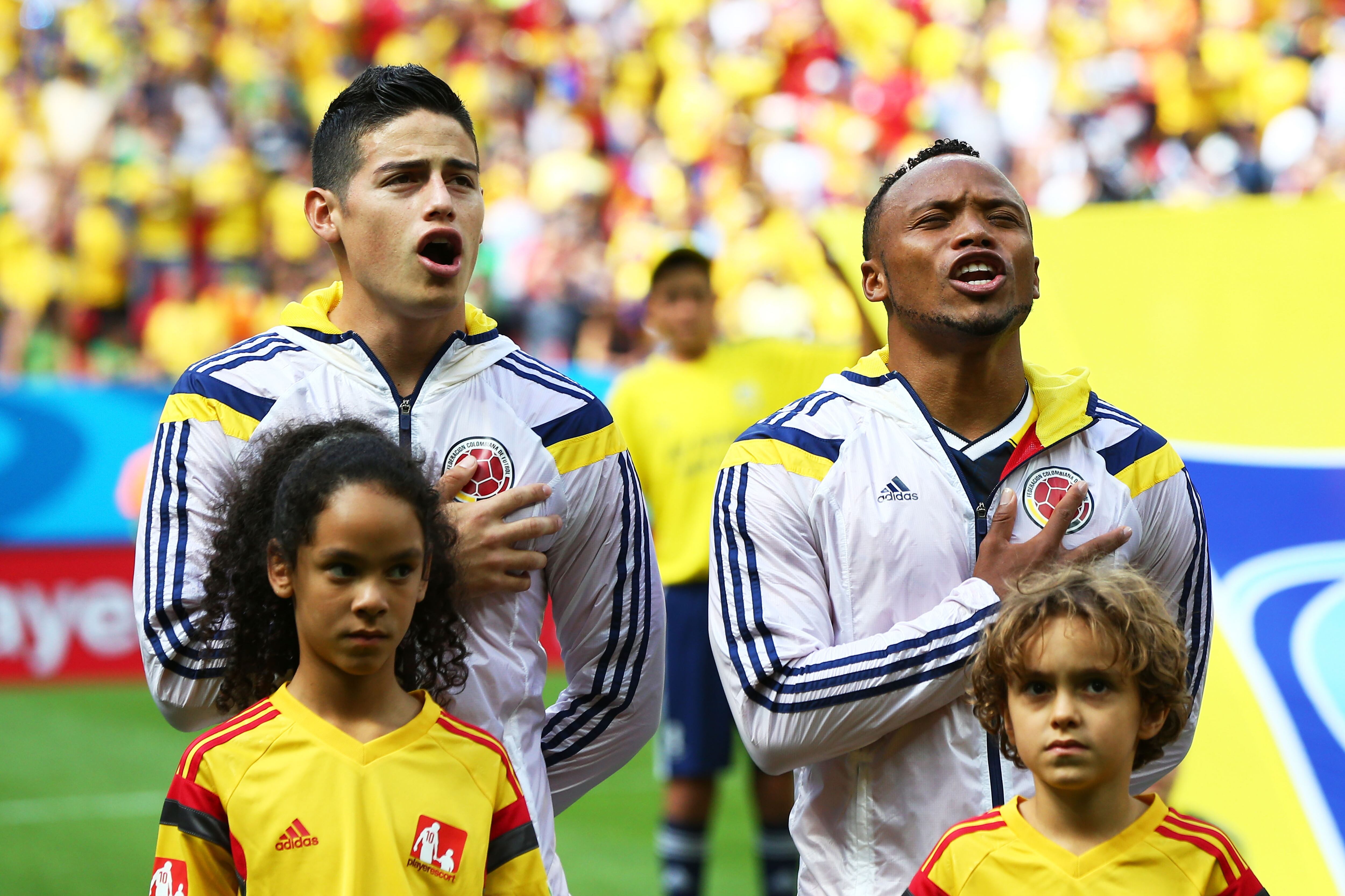 James Rodríguez (L) y Juan Camilo Zúñiga de Colombia cantan el Himno Nacional antes del partido del Grupo C de la Copa Mundial de la FIFA Brasil 2014 entre Colombia y Costa de Marfil en el Estadio Nacional el 19 de junio de 2014 en Brasilia. , Brasil. (Foto de Elsa/Getty Images)