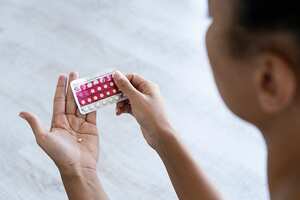 Close-up of young woman's hand holding birth control pills