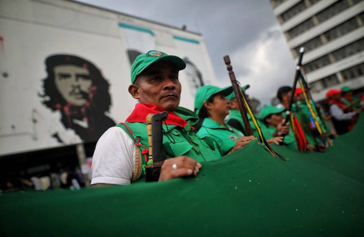 Un grupo de indígenas sostiene la bandera para tratar de secarla después de la  la lluvia. Foto: Esteban Vega/Semana
