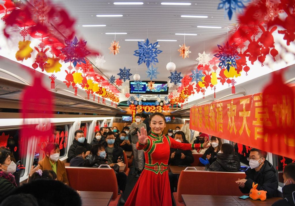 Un miembro del grupo Ulan Muqir baila en el tren bala Fuxing G2457, que viaja de Beijing a Hohhot, el 14 de enero de 2023. El tradicional festival chino Xiaonian, que marca el inicio de la cuenta regresiva para el Año Nuevo Lunar chino, cae el sábado. en el norte de China. Los azafatos y miembros de la compañía Ulan Muqir entregaron obsequios a los pasajeros y actuaron en el tren para conmemorar el festival Xiaonian. (Foto de Liu Lei/Xinhua vía Getty Images)