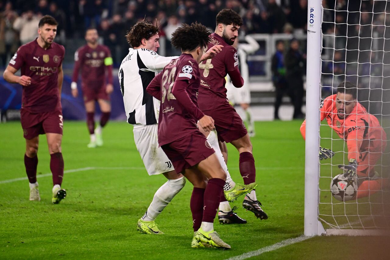 El portero brasileño del Manchester City #31 Ederson (D) se lanza a por el balón mientras el delantero serbio de la Juventus #09 Dusan Vlahovic (2L) marca el primer gol de la Juventus durante el partido de fútbol de la UEFA Champions League, fase de liga día 6, entre la Juventus (ITA) y el Manchester City (ENG) en el estadio Allianz de Turín, el 11 de diciembre de 2024.
