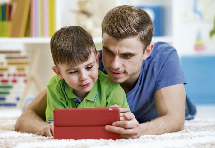Niño disfrutando de la tecnología con el papá.