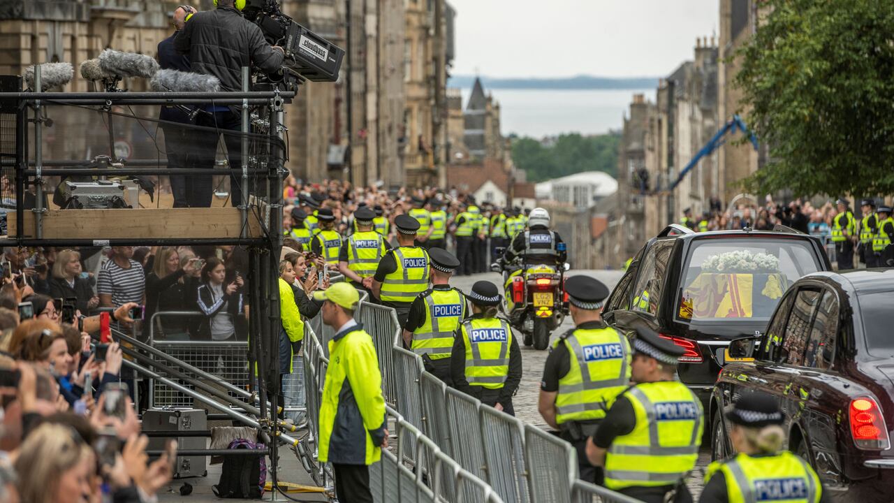 The hearse carrying the coffin of Queen Elizabeth II, draped in the Royal Standard of Scotland, is driven along the Royal Mile in Edinburgh, en-route towards the Palace of Holyroodhouse, on September 11, 2022. - The coffin carrying the body of Queen Elizabeth II left her beloved Balmoral Castle on Sunday, beginning a six-hour journey to the Scottish capital of Edinburgh. (Photo by Andrew O'Brien / POOL / AFP)