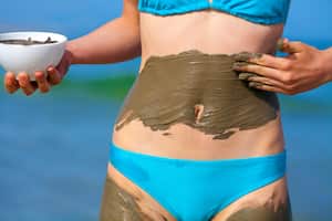 Woman smearing mud mask on the body