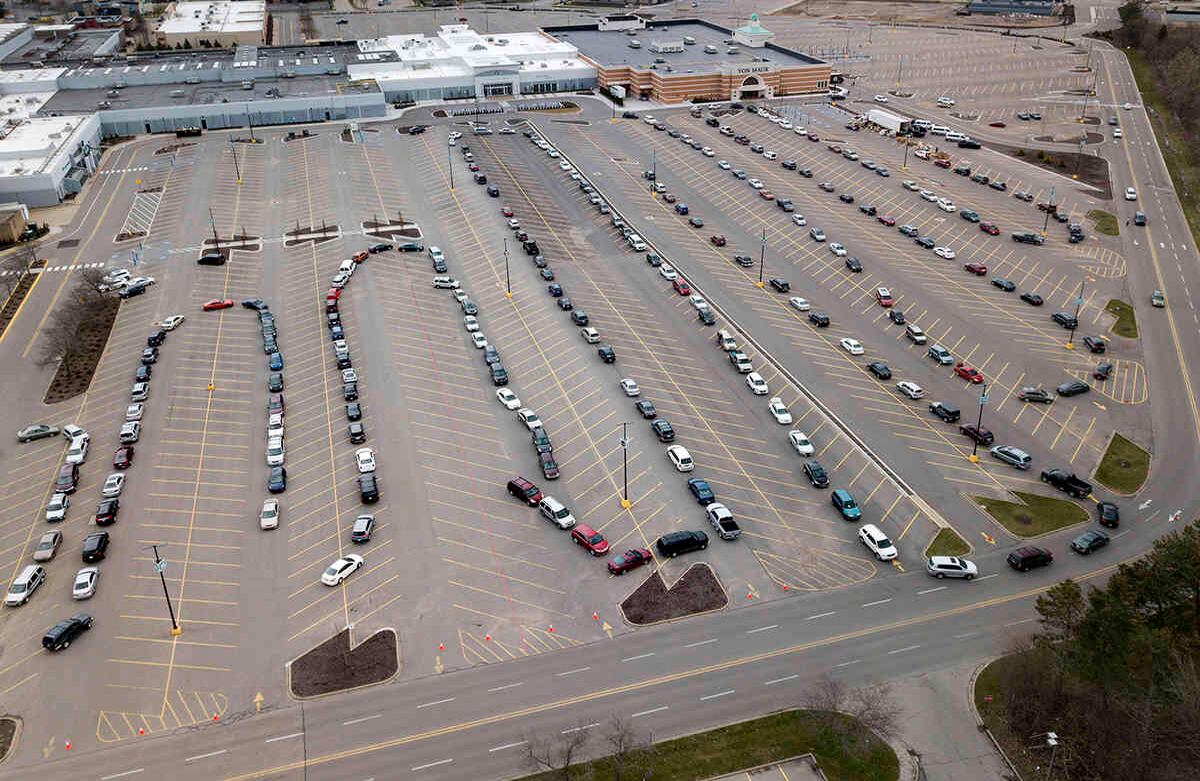 Los coches se alinean en el estacionamiento de una despensa de comida en Woodland Mall en Grand Rapids, ciudad del estado de Míchigan, el jueves 1 de abril de 2020. La Guardia Nacional ayudó a distribuir la comida en el sitio que estaba dirigido por Feeding America West Michigan. La despensa es una de las muchas instaladas después de que el nuevo coronavirus llegara a Michigan. Foto: Neil Blake/The Grand Rapids Press vía AP. 