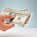 Mano sosteniendo una selección de billetes de dólar estadounidense