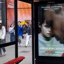 Passing people interacting with an advertising poster on a bus shelter for the Netflix drama 'Adolescence', the story of which is sparking conversations in public and govenrment around the subject of toxic masculinity and children's access to dangerous and misoginistic content on the internet and social media on 23rd March 2025 in London, United Kingdom. (photo by Mike Kemp/In Pictures via Getty Images)