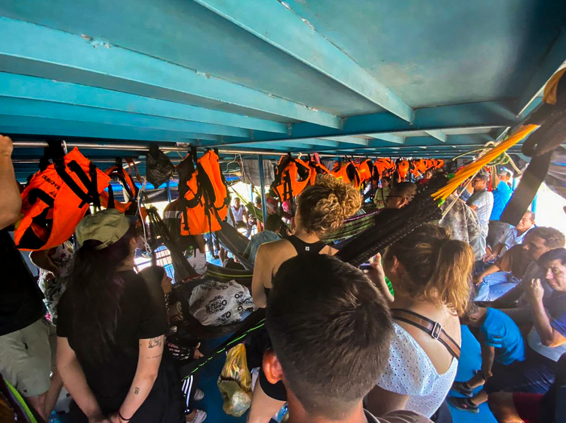 Turistas extranjeros y peruanos esperan en el bote donde fueron detenidos en la comunidad de Cuninico en Loreto, al norte de Perú, el 4 de noviembre de 2022. - Indígenas en la Amazonía peruana detuvieron a un grupo de turistas extranjeros y peruanos que viajaban en un bote fluvial para protestar por la falta de ayuda del gobierno tras un derrame de petróleo en la zona, informaron el jueves medios locales. (Foto por Ángela RAMÍREZ / AFP)