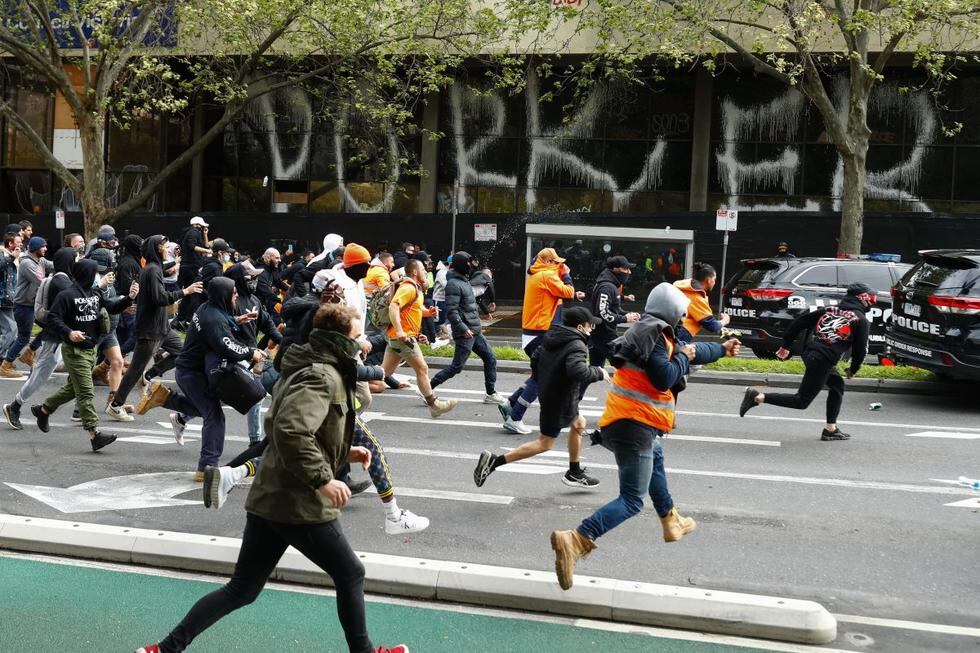 Los manifestantes persiguen a la policía durante una protesta contra la obligación de las vacunas contra el coronavirus en Melbourne, Australia, el 21 de septiembre de 2021. (STR / AFP).