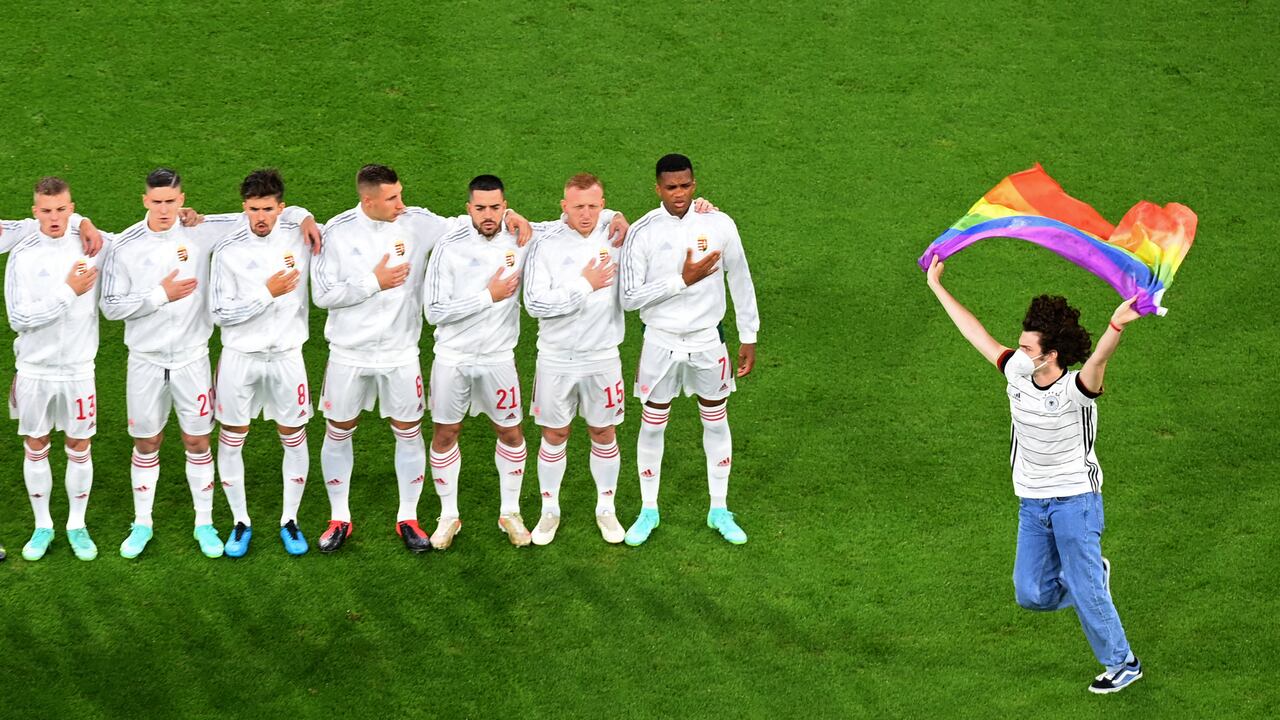 A person waving the rainbow flag runs on the pitch as the Hungary players line up for the national anthems the UEFA EURO 2020 Group F football match between Germany and Hungary at the Allianz Arena in Munich on June 23, 2021. (Photo by Matthias Hangst / POOL / AFP)