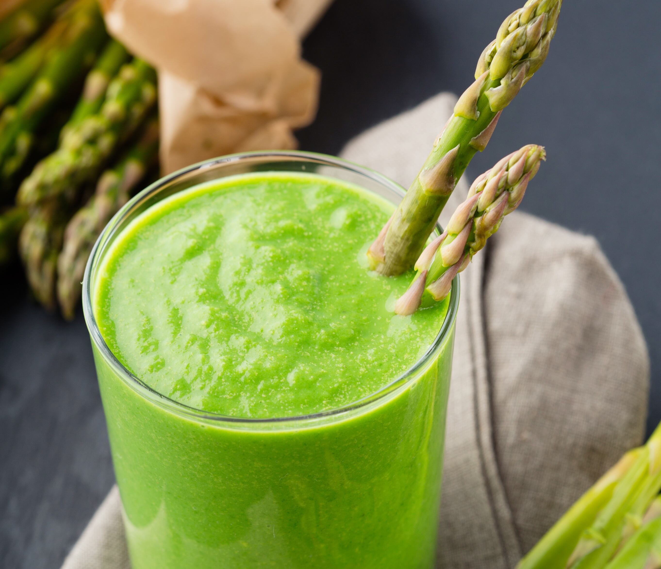 Healthy green smoothie with asparagus and cucumber on black background, selective focus. Vegan, raw food, detox lifestyle.