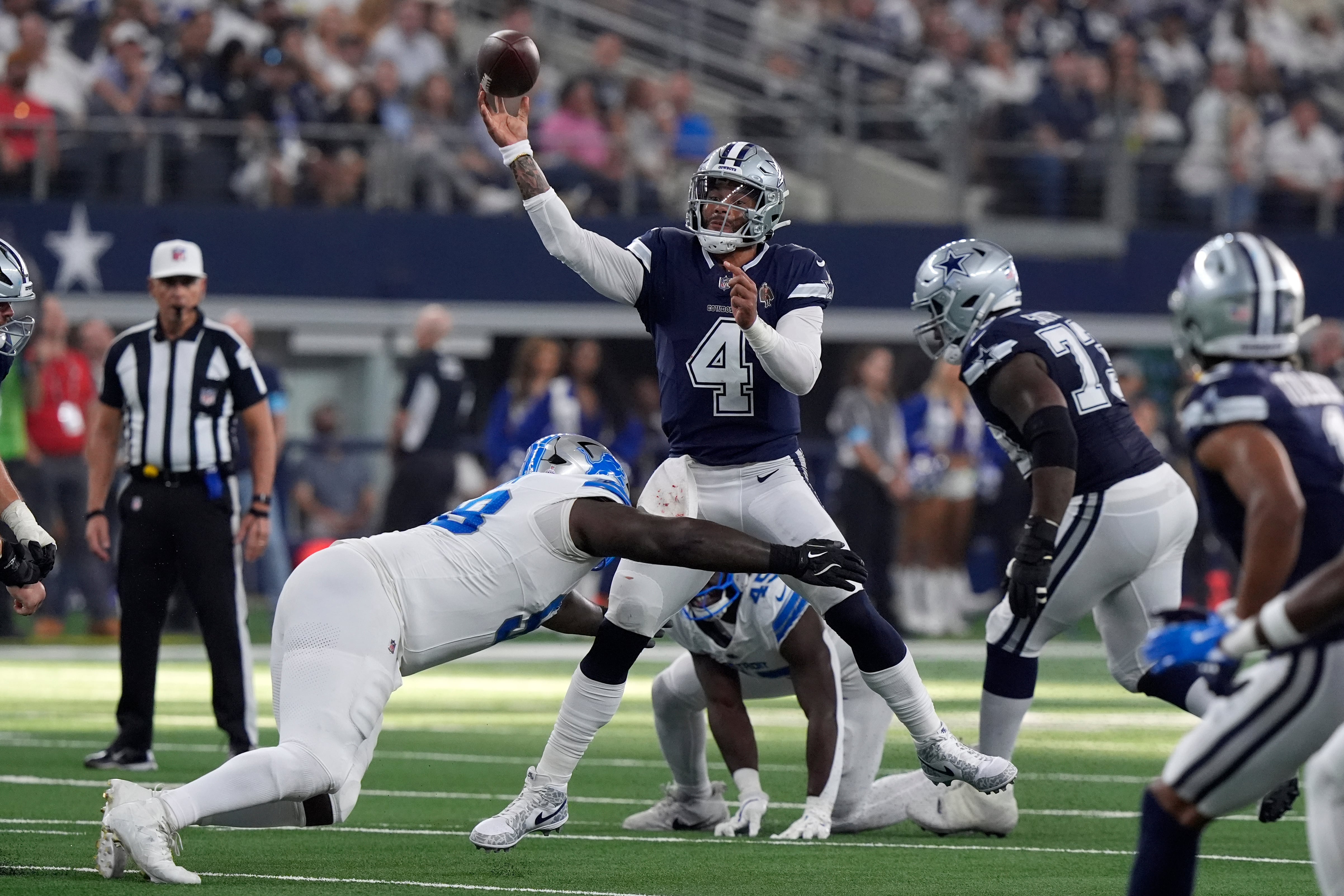 El mariscal de campo de los Dallas Cowboys, Dak Prescott (4), lanza un pase bajo la presión de las acometidas de los Detroit Lions en la segunda mitad de un partido de fútbol americano de la NFL en Arlington, Texas, el domingo 13 de octubre de 2024.