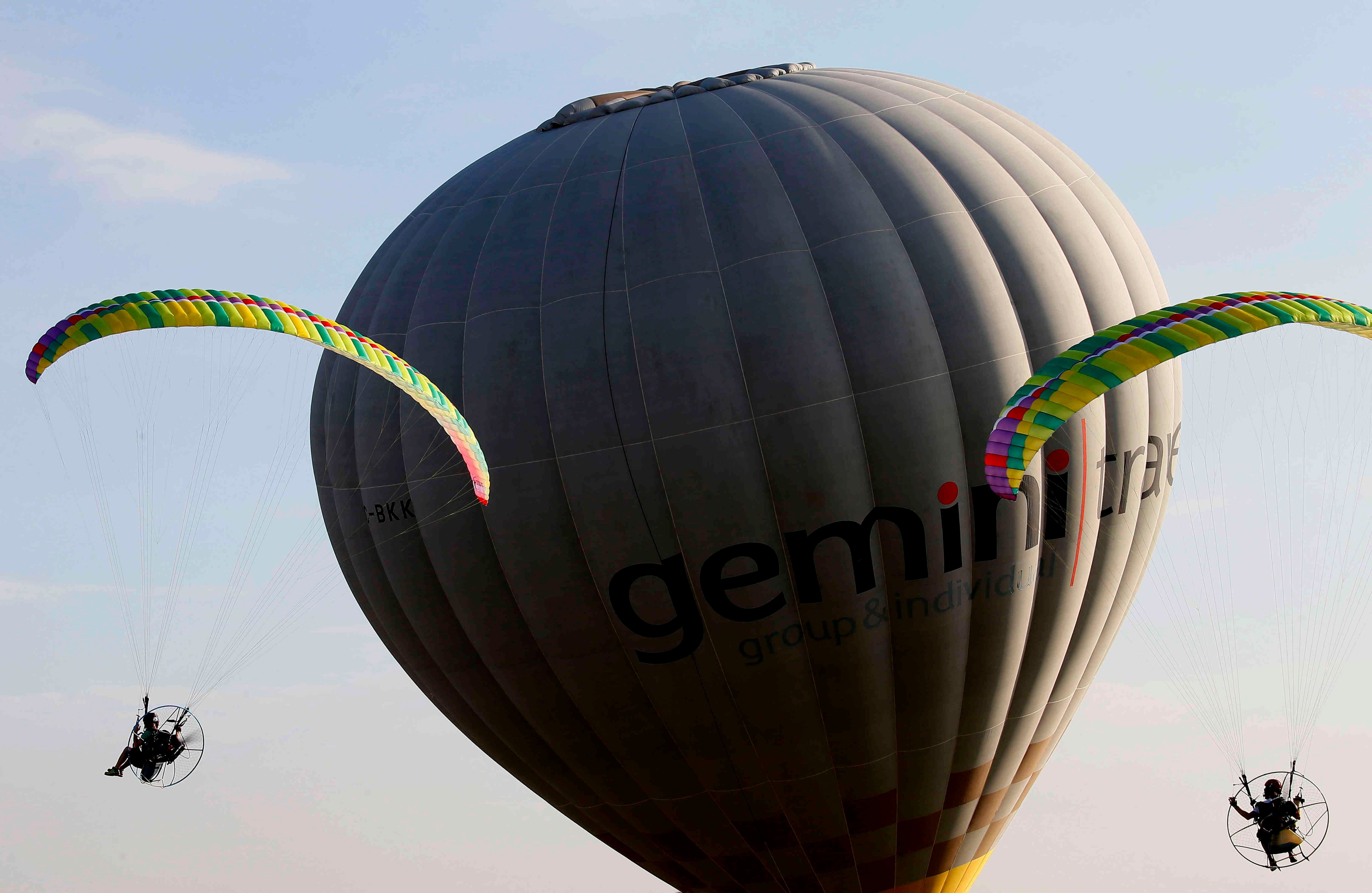 Los paragliders vuelan a través de un globo de aire caliente al comienzo del 21º Festival de Globos de Aire Caliente en la antigua base de la Fuerza Aérea de los Estados Unidos en Clark, provincia de Pampanga al norte de Manila, Filipinas el jueves 9 de febrero de 2017. Diferentes países están participando en el festival. (Foto AP / Bullit Márquez)